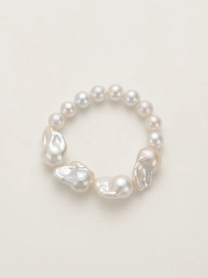 Flatlay view of the circular large baroque pearl beaded elastic bracelet with iridescent luster.