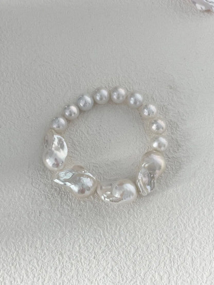 Large baroque freshwater pearl elastic bracelet resting on a white textured background.