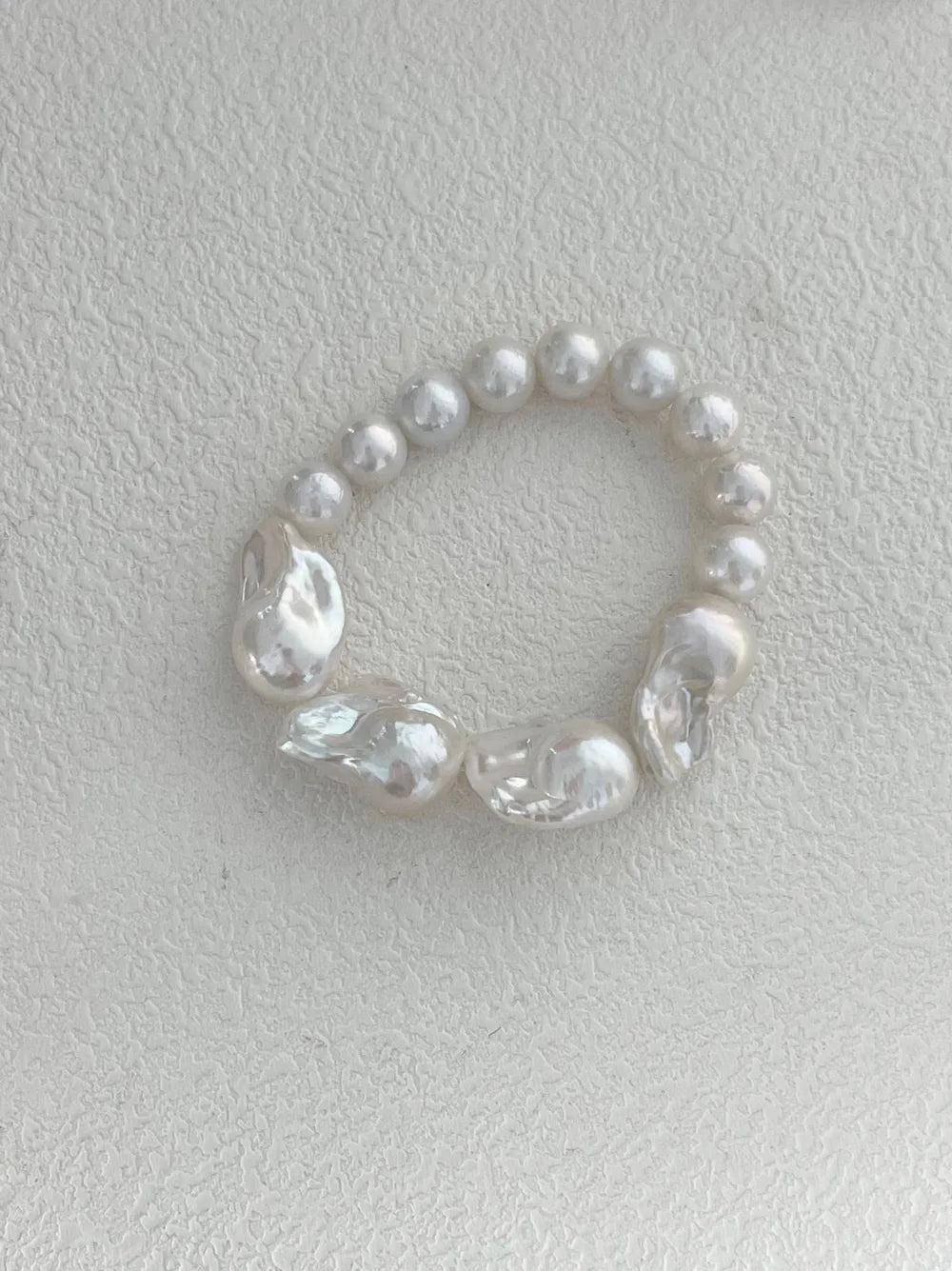 Overhead view highlighting the raw organic textures and round pearl splicing of the bracelet.