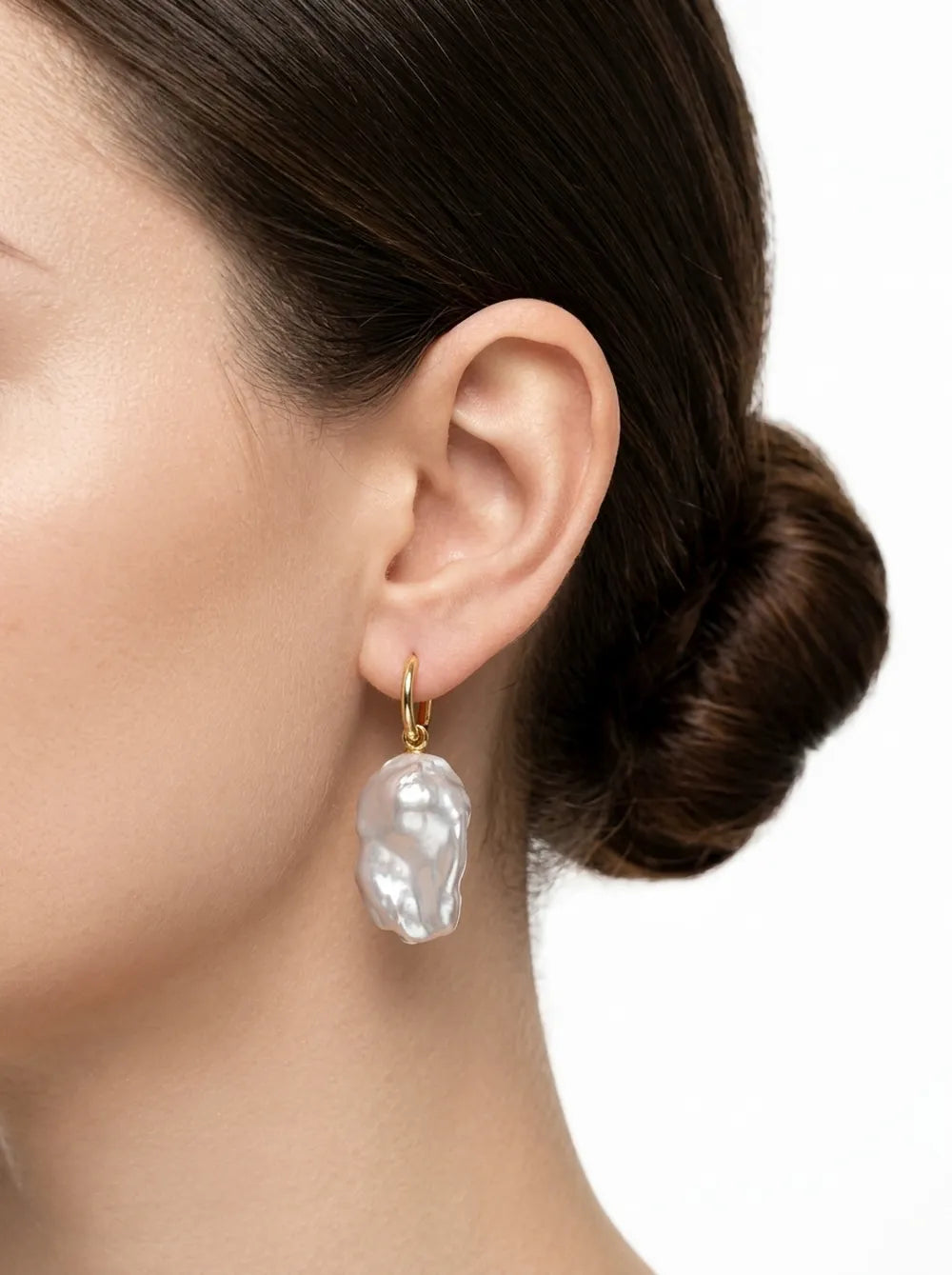 Model with hair in a bun wearing the large flame-tailed baroque pearl huggie earring.