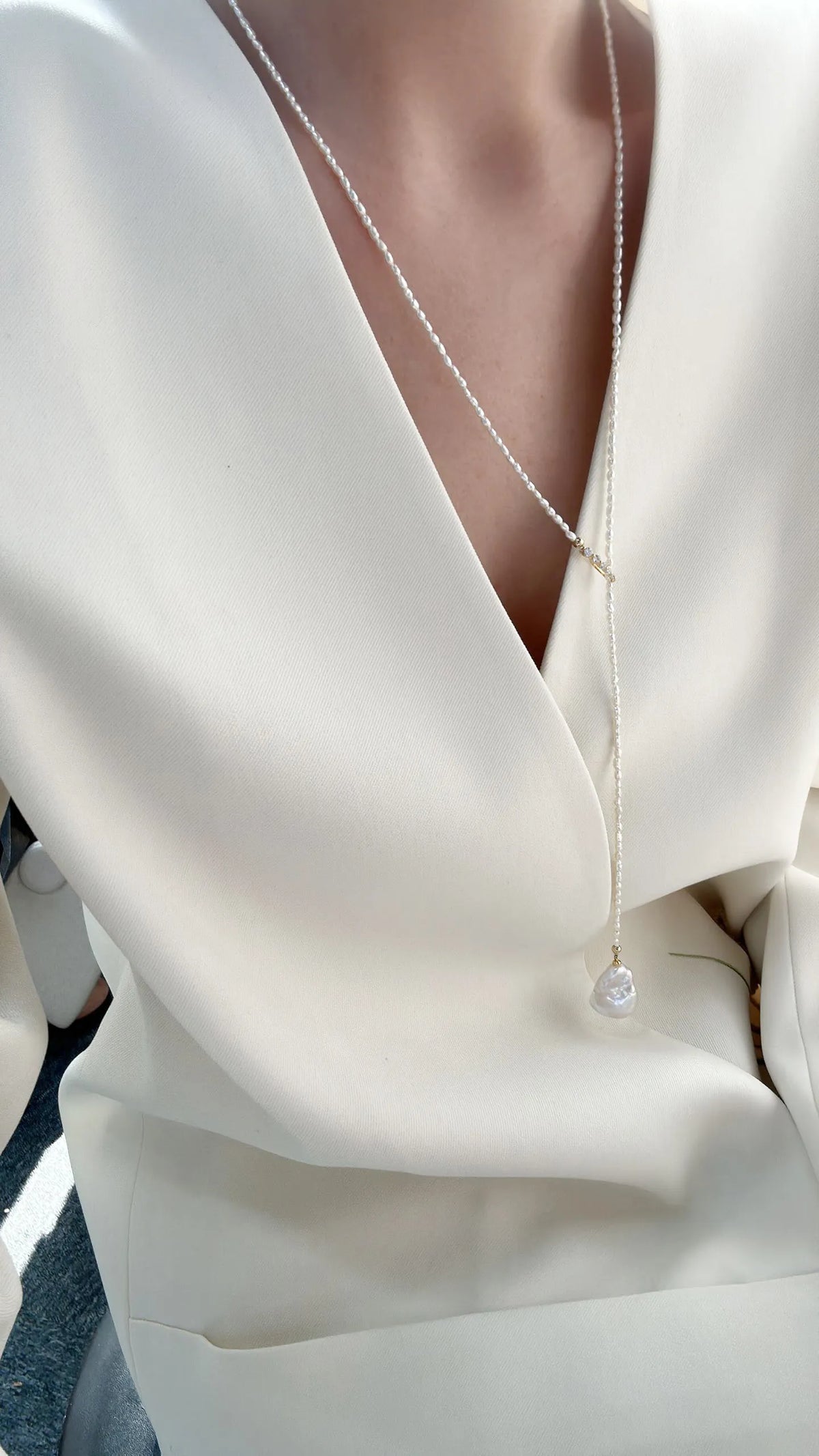 Close-up of model holding the Keshi pearl drop, styled with a statement baroque pearl ring and necklace.