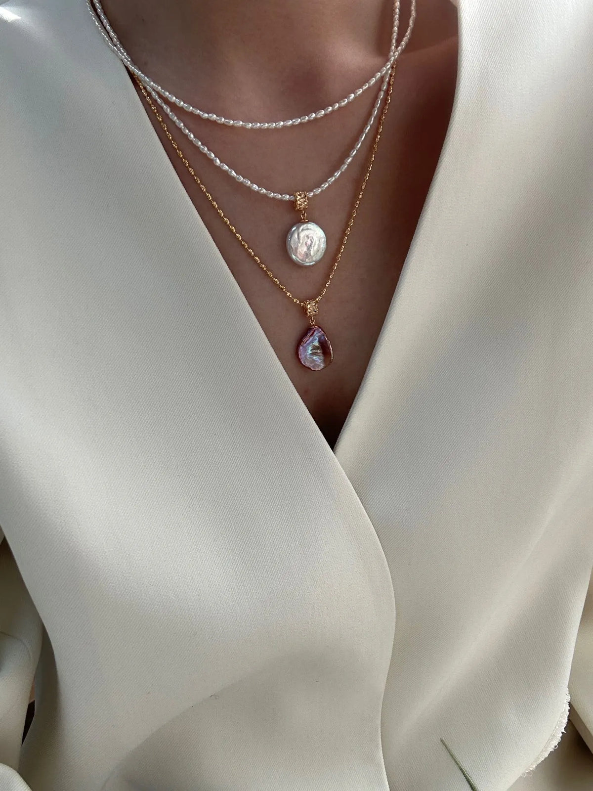 Model wearing a layered pearl necklace set featuring the Roman coin pearl choker.