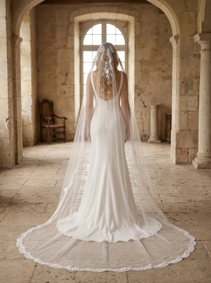 Long cathedral mantilla veil with leafy scalloped lace border trailing down a white sheath bridal gown