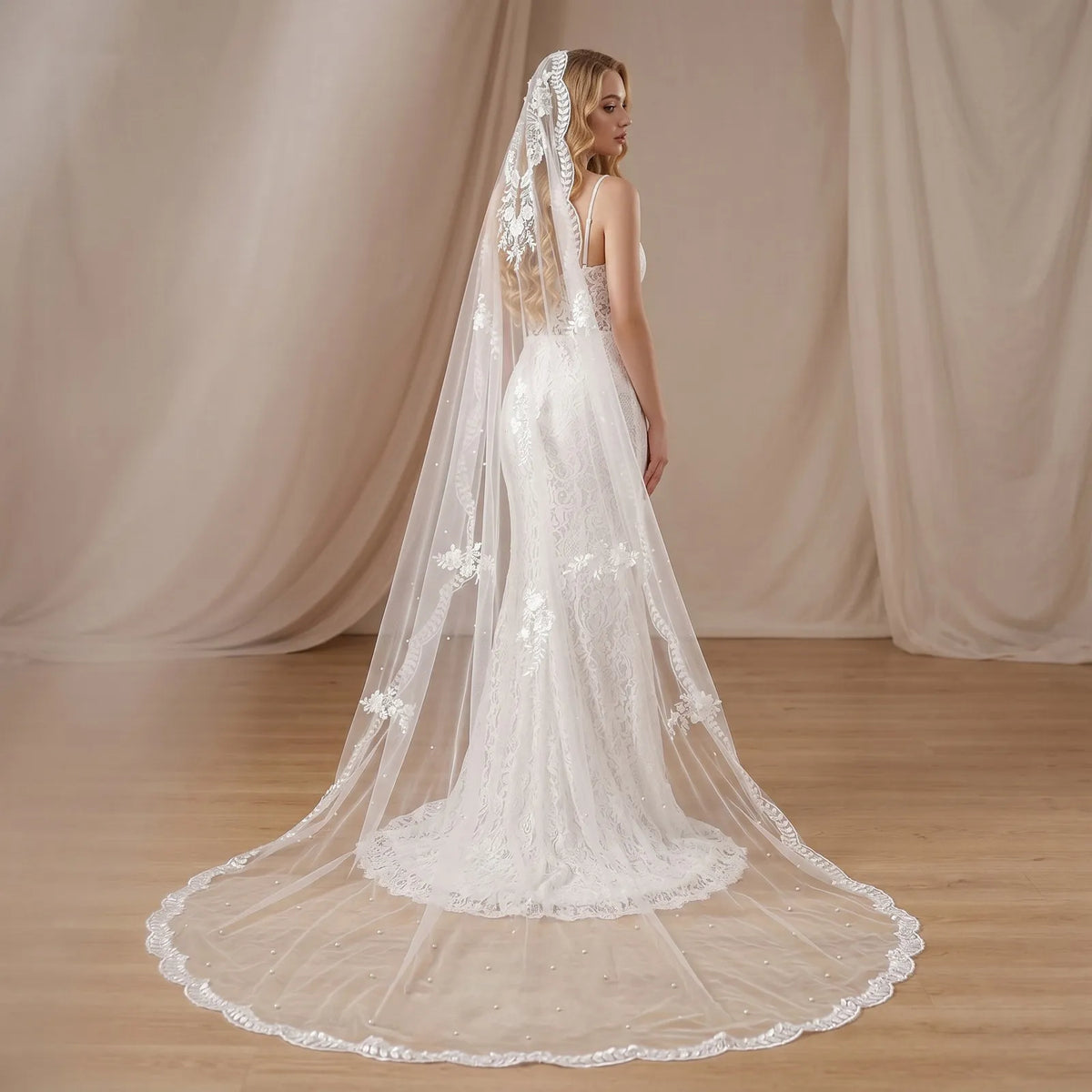 Full length back view of cathedral veil spread out on wooden floor showing scalloped leaf lace edge