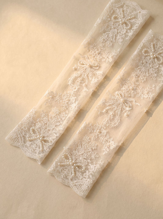 Elbow‑length finger‑less lace bridal gloves with floral embroidery bow appliqué worn with wedding dress