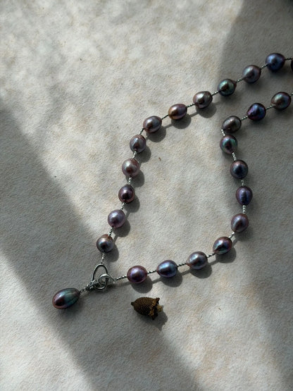Metallic violet baroque pearl Y-necklace showing deep iridescent luster under bright sunlight.