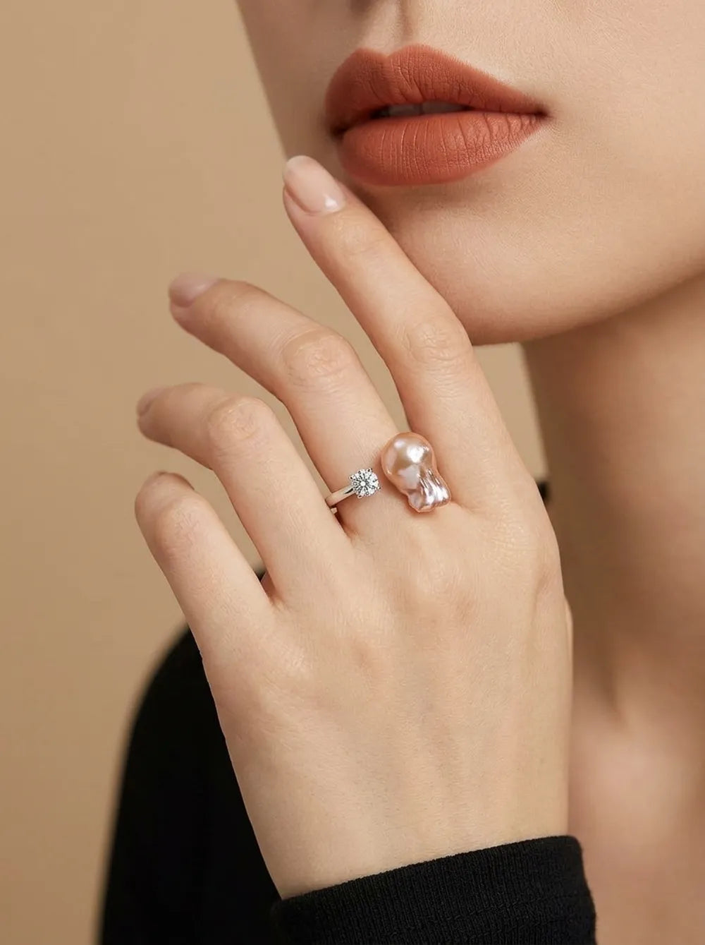 Model holding hand to face displaying the diamond bean baroque pearl open ring on index finger.