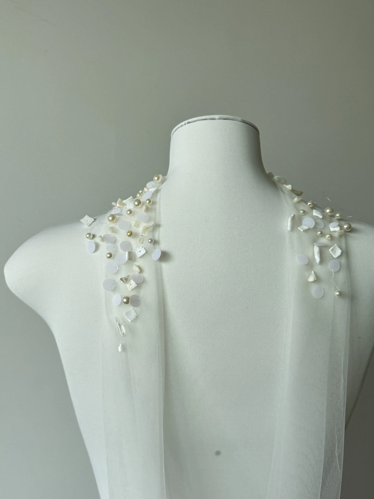 Modern coastal mermaid style halter bridal cape veil featuring exquisite natural seashell embellishments, iridescent mother-of-pearl flakes, and clear glass bead embroidery around the neckline.