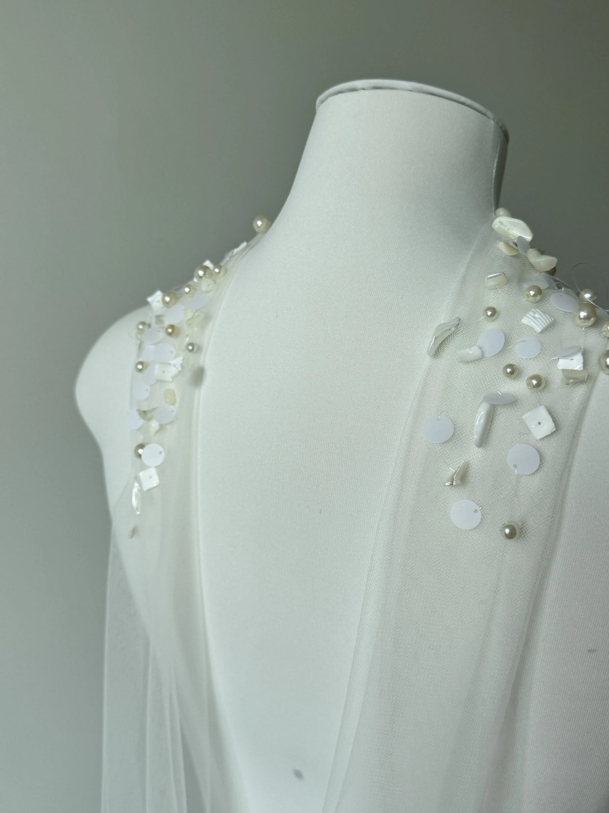 Modern coastal mermaid style halter bridal cape veil featuring exquisite natural seashell embellishments, iridescent mother-of-pearl flakes, and clear glass bead embroidery around the neckline.