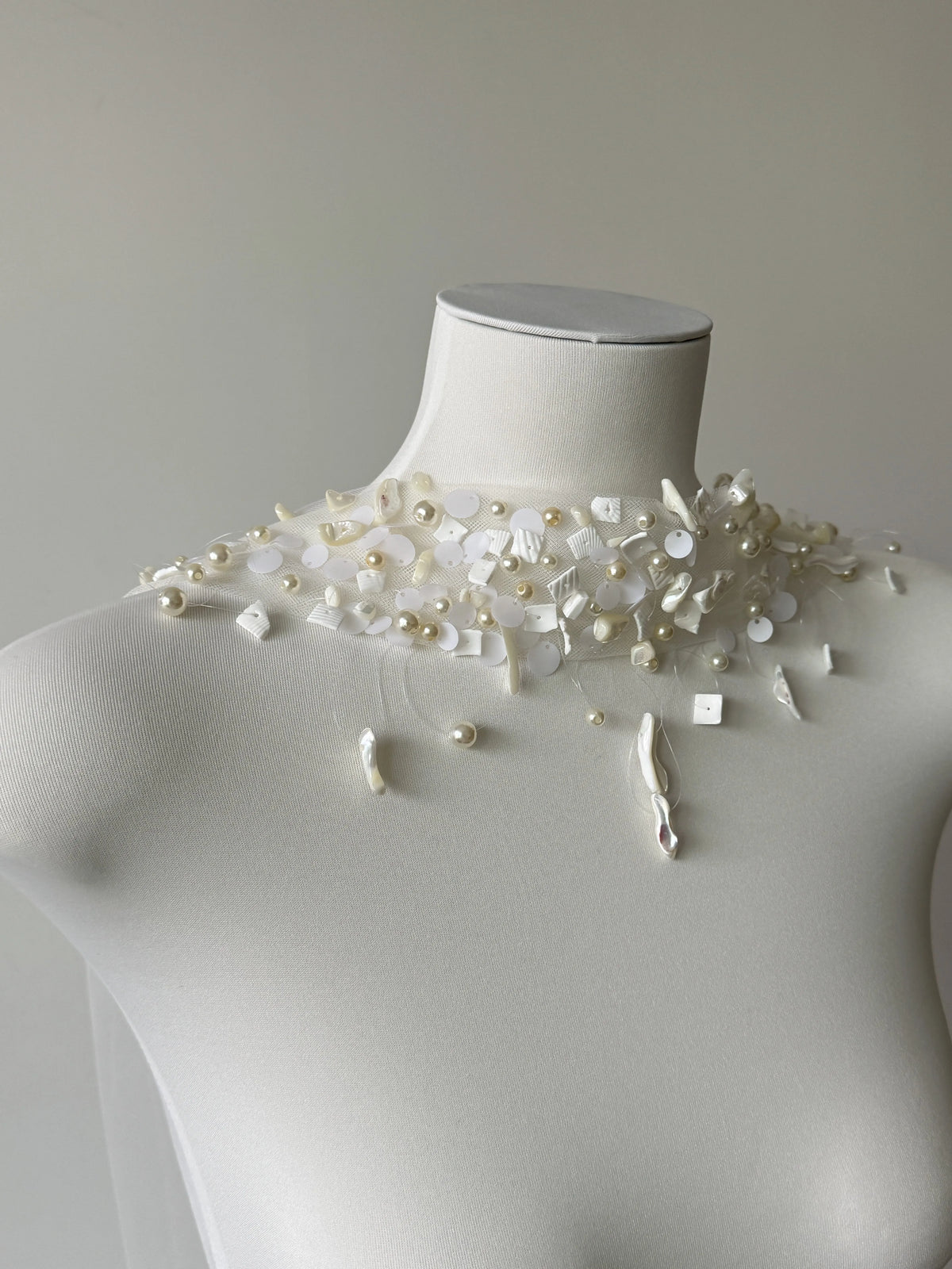 Modern coastal mermaid style halter bridal cape veil featuring exquisite natural seashell embellishments, iridescent mother-of-pearl flakes, and clear glass bead embroidery around the neckline.