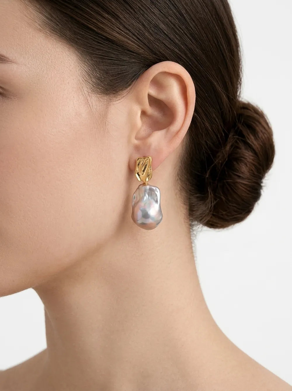 Model with hair in a bun wearing the molten metal large baroque pearl drop earring in 18k gold over S925 silver.