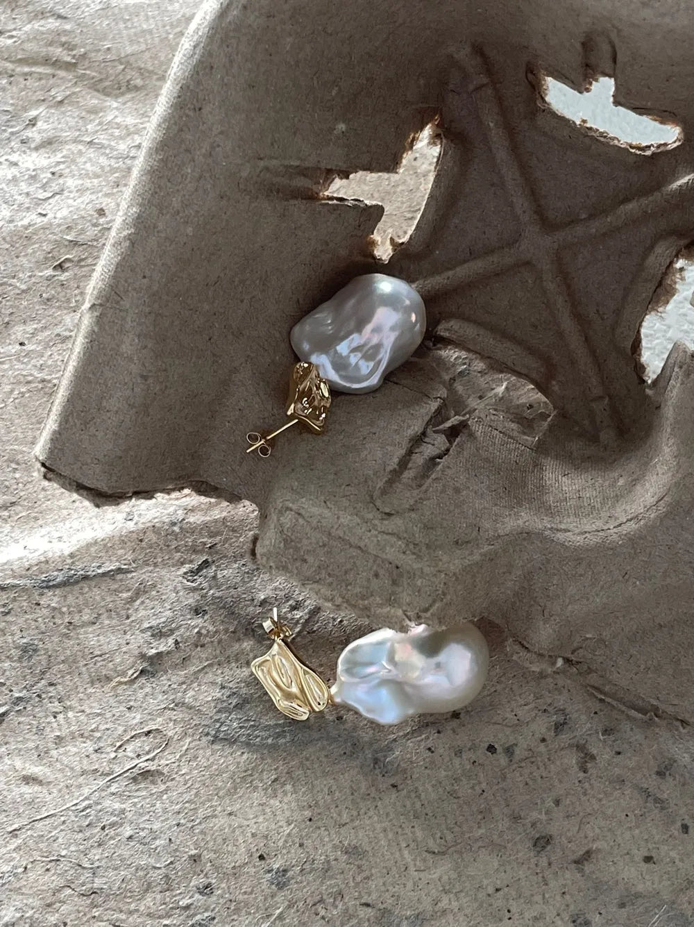 Close-up shot highlighting the molten liquid gold texture studs and natural baroque pearls.