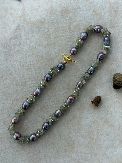 Oval flatlay of natural moonstone and baroque pearl necklace with acorn props.