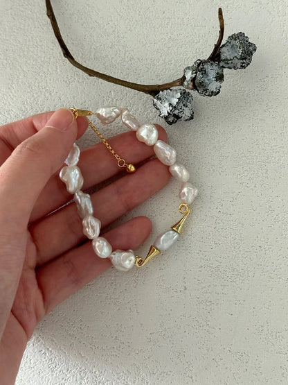 Hand holding the moustache baroque freshwater pearl bracelet showing gold hardware details.