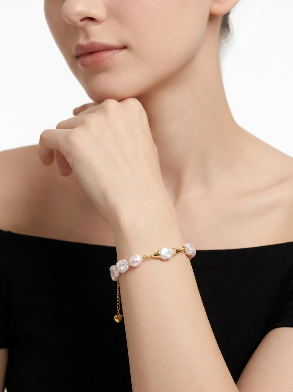 Model wearing the moustache metal-capped baroque pearl bracelet on wrist with heart charm.