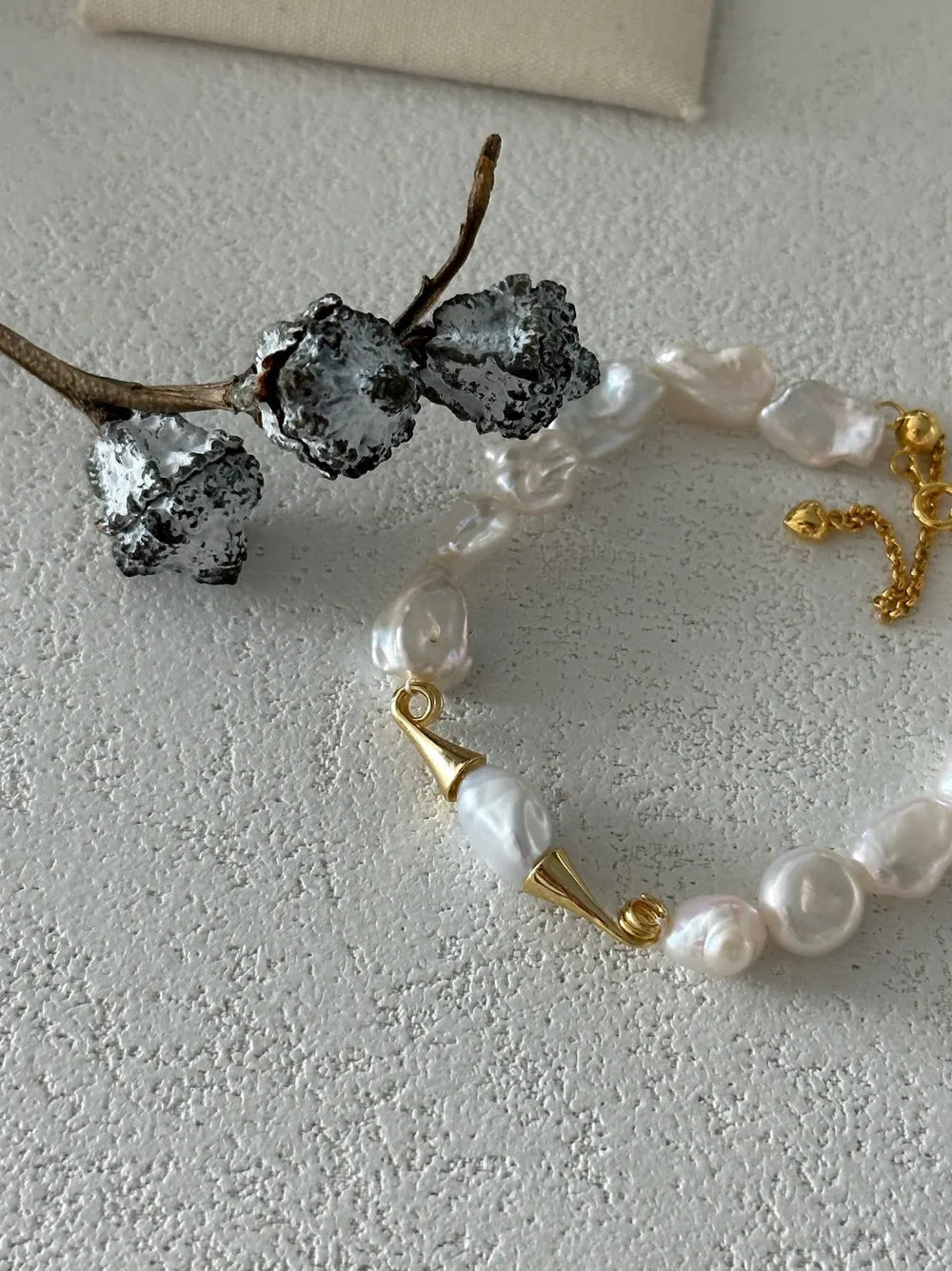 Overhead close-up shot highlighting the gold horn caps and natural baroque pearl texture.