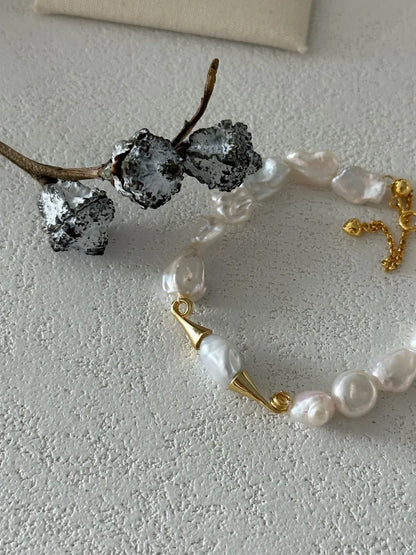 Overhead close-up shot highlighting the gold horn caps and natural baroque pearl texture.