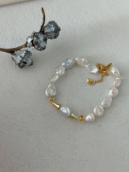 Moustache baroque pearl bracelet displayed next to a cotton pod prop on white background.