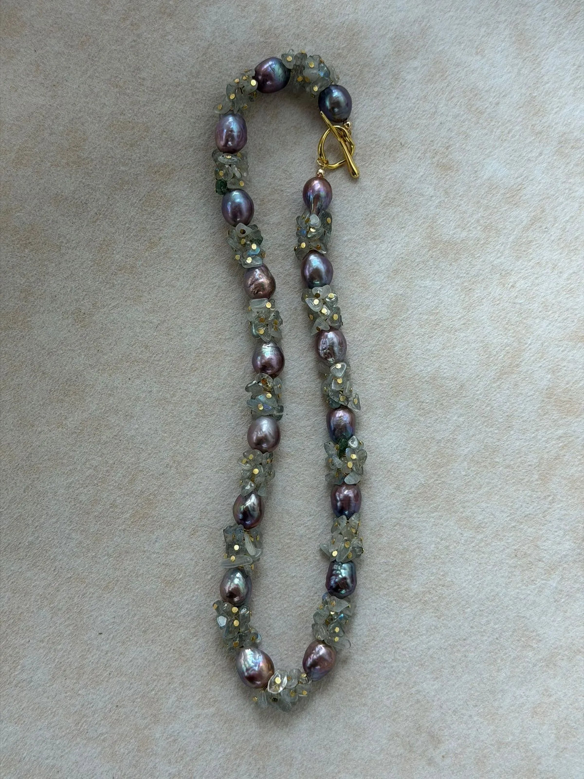 Vertical S-curve layout of natural moonstone and purple baroque pearl necklace.