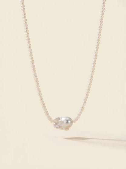 Product studio shot of the organic baroque freshwater pearl choker on a warm white background.