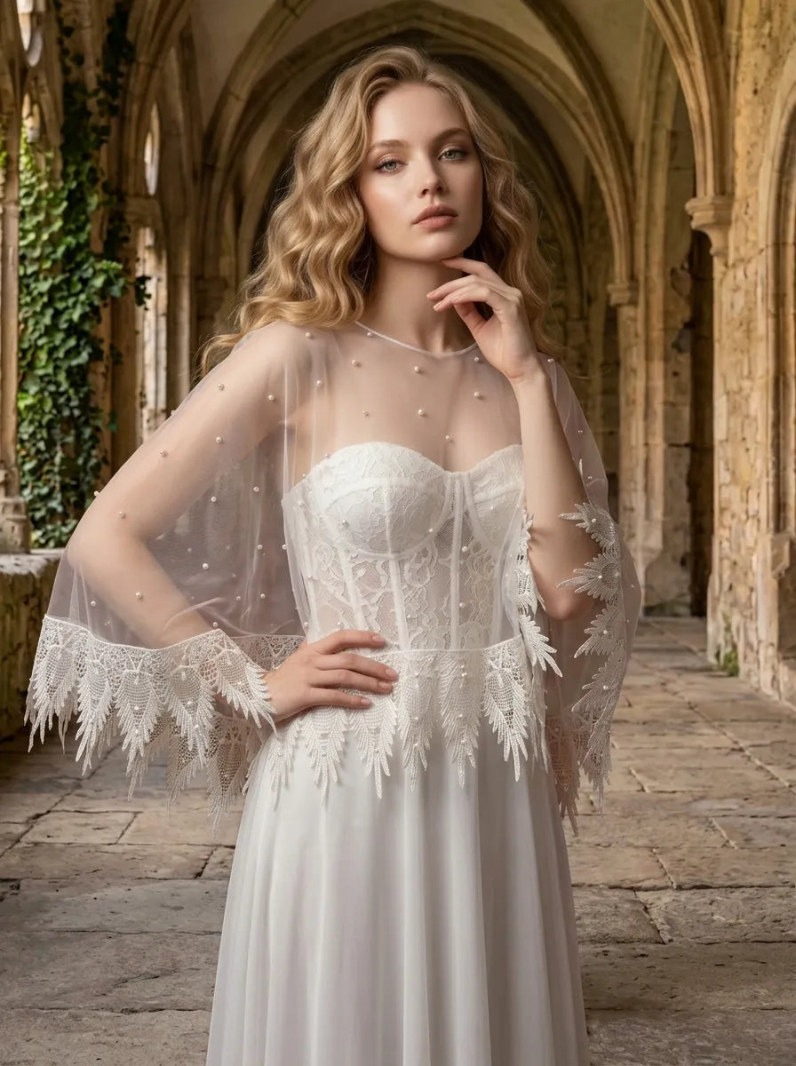 Bride wearing pearl embellished sheer capelet over sweetheart lace wedding gown in historic archway