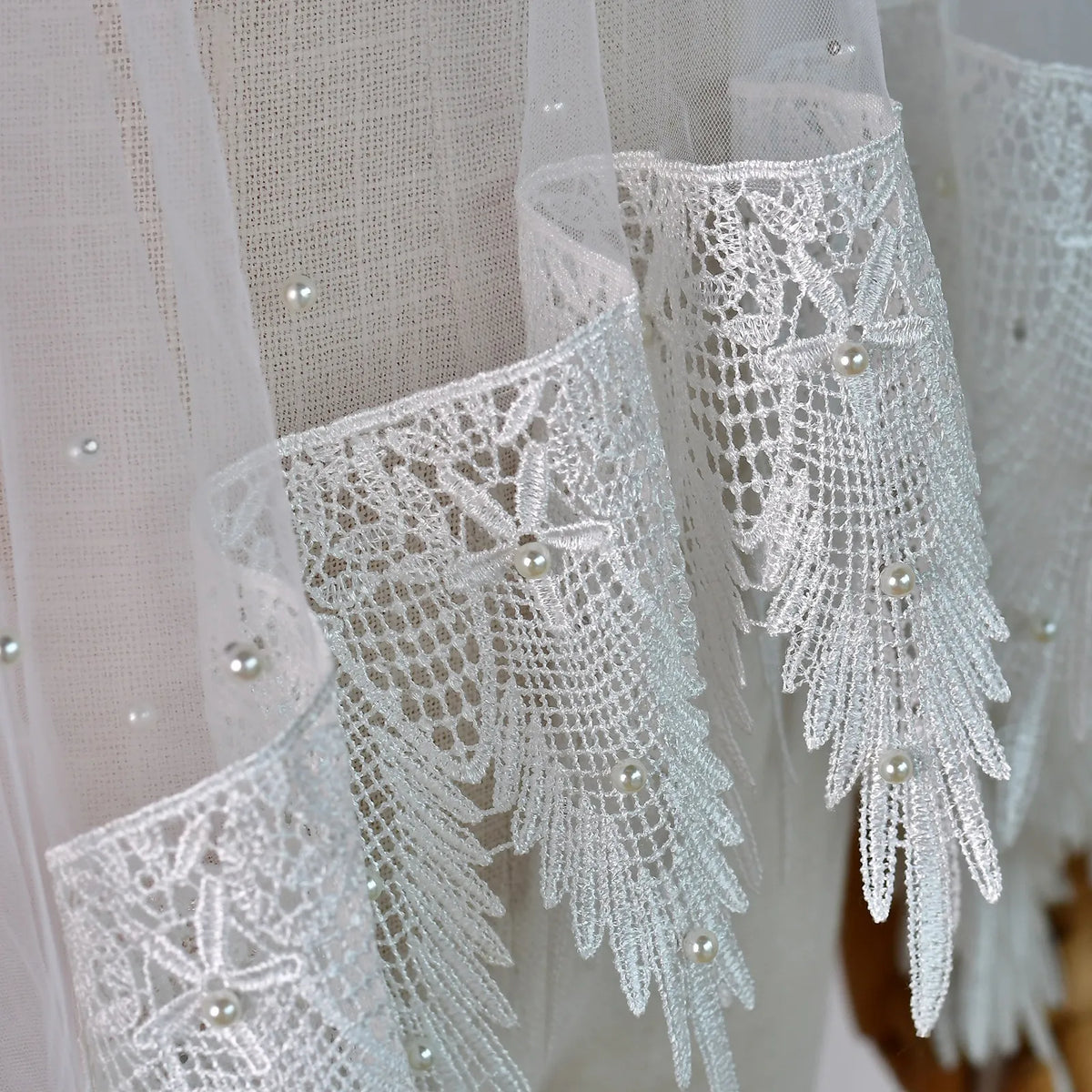 Extreme close up showing faux pearls studded on soft tulle and pointed crochet lace edging
