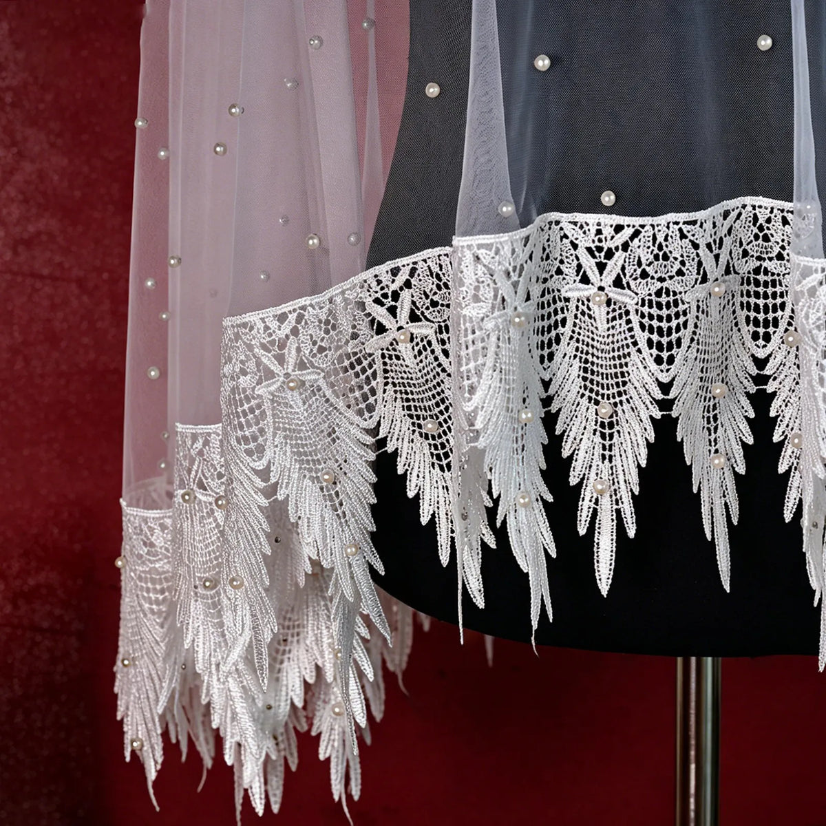 Close up view of layered sheer tulle drape featuring pointed crochet lace hem with pearl accents