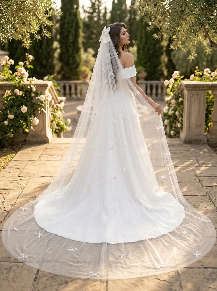 Rear view of bride in off-the-shoulder dress with 300cm pearl ribbon bow cathedral veil in garden