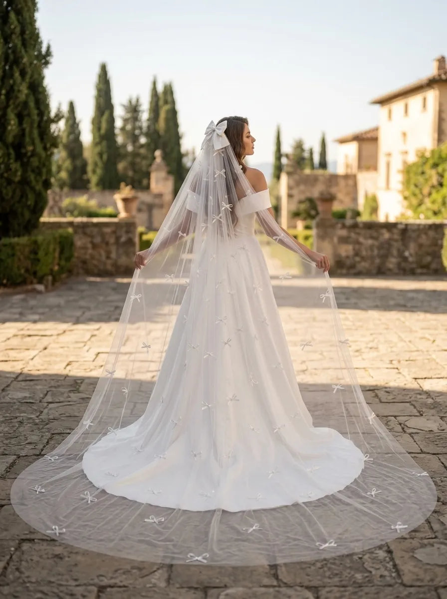 Full length view of bride walking outdoors with wide bow-dusted cathedral veil trailing behind