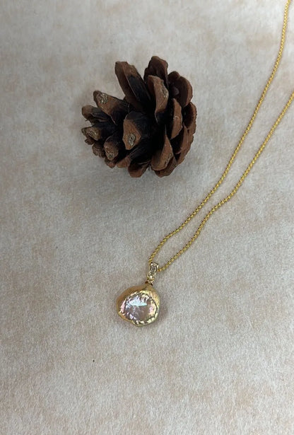 Petal baroque pearl pendant on metallic beaded chain against light background