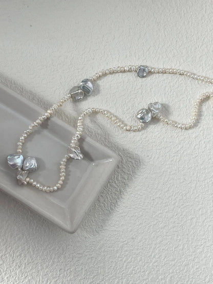 Close-up of petal-shaped freshwater pearl necklace displayed on a sleek ceramic tray