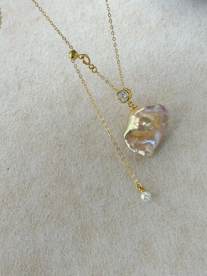 Macro photograph of golden rainbow baroque pearl featuring bezel-set CZ connector.