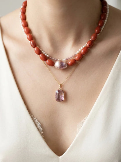 Model wearing red jasper baroque pearl choker layered with a gold crystal pendant necklace