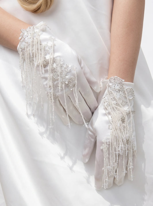 Close-up of retro baroque white satin short bridal gloves featuring handcrafted beadwork, sequins, and cascading fringe strands.