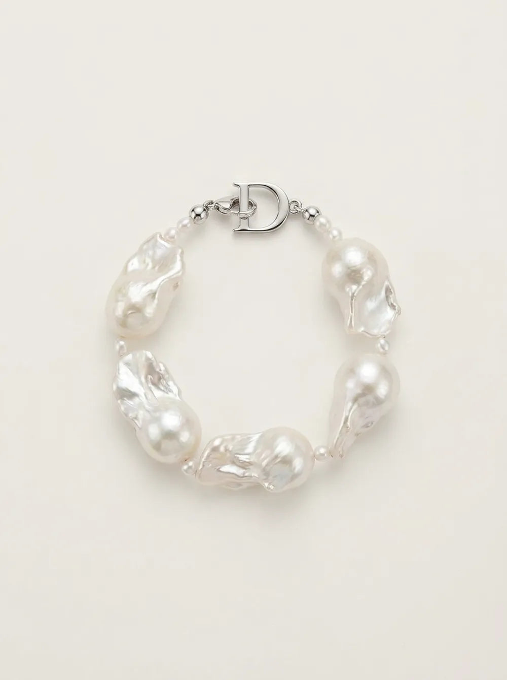 Flatlay view of the circular rice and large baroque pearl bracelet featuring S925 silver D clasp.