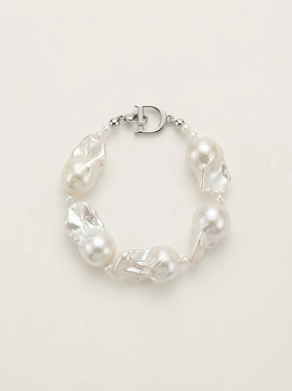 Flatlay view of the circular rice and large baroque pearl bracelet featuring S925 silver D clasp.