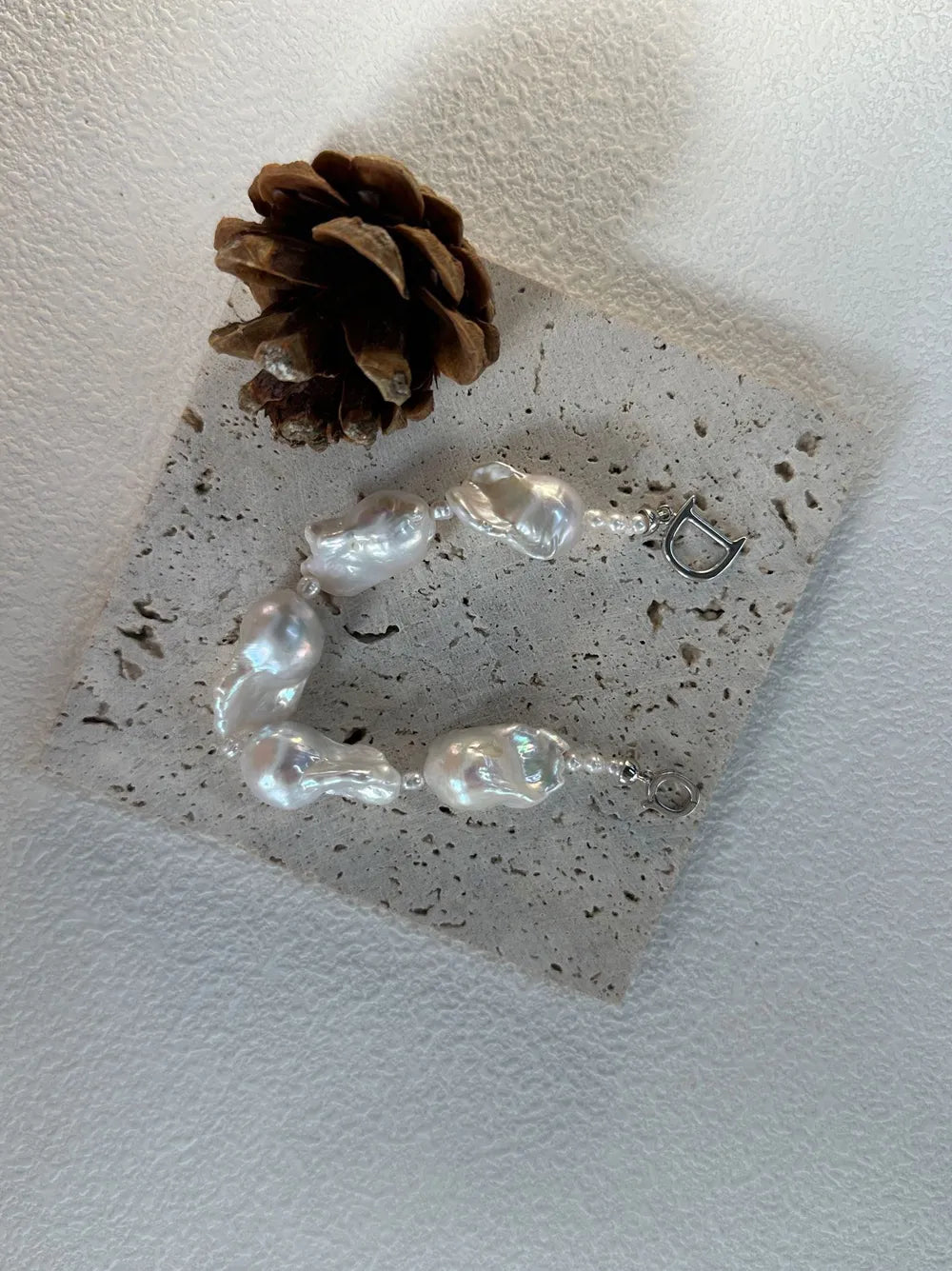 U-shaped view of the rice and large baroque pearl strand bracelet on stone tile showing nacre luster.