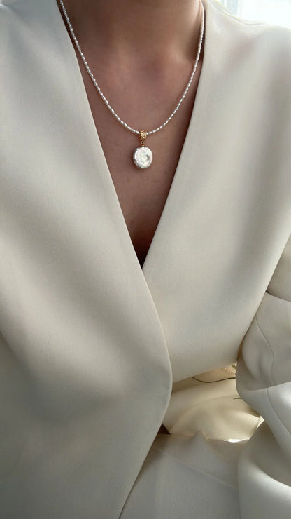 Close-up of model showcasing the Roman coin pearl pendant resting on the collarbone.