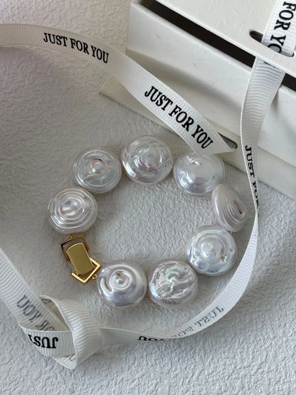 Flat button coin baroque pearl bracelet arranged on white background with custom ribbon prop.