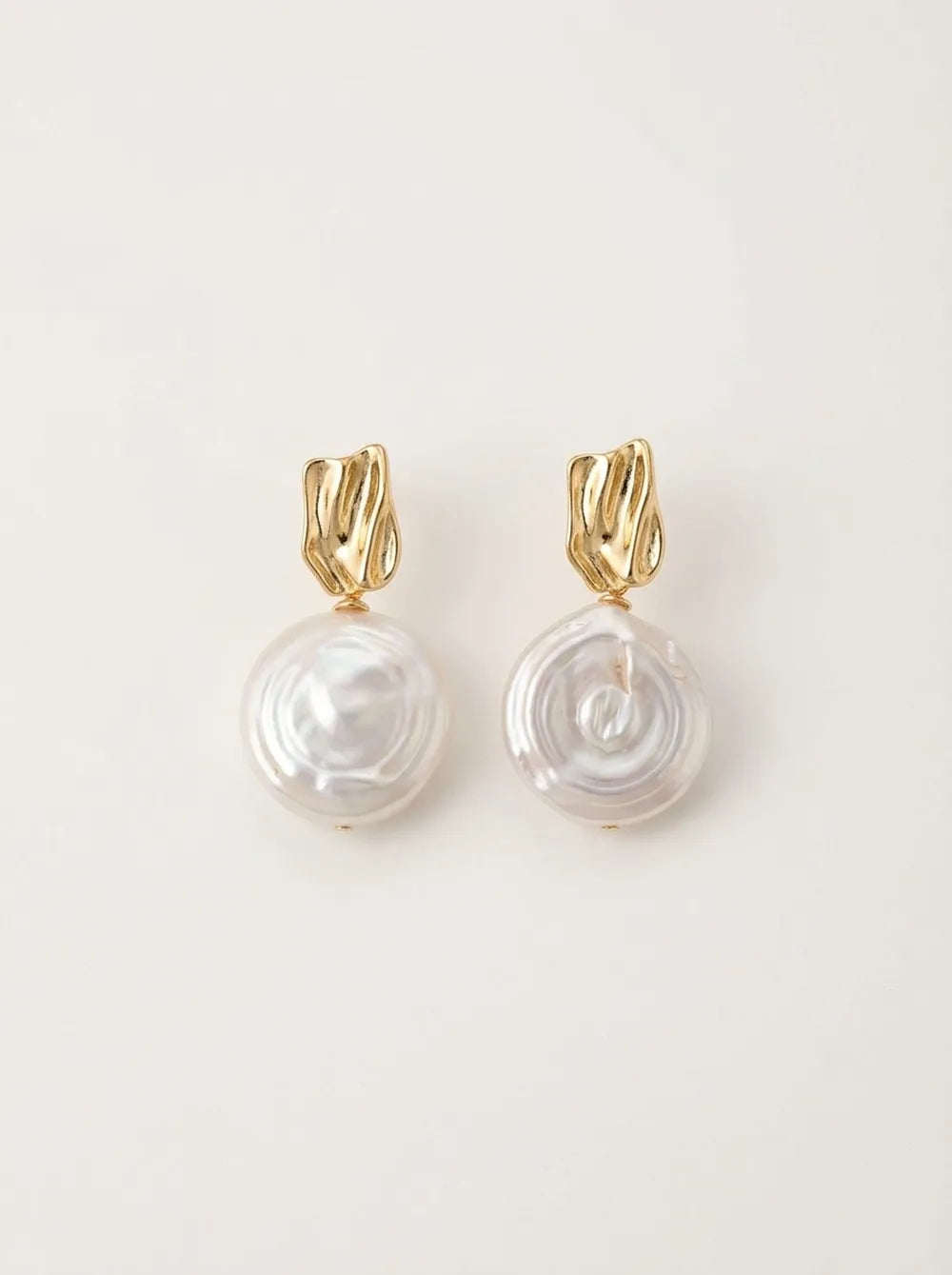 Profile of model with hair in a bun wearing the Roman Holiday coin baroque pearl drop earring