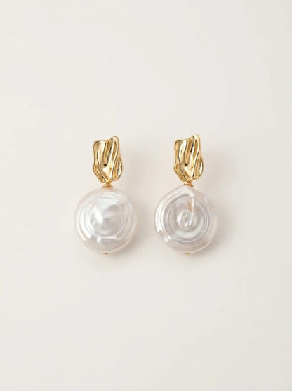 Profile of model with hair in a bun wearing the Roman Holiday coin baroque pearl drop earring