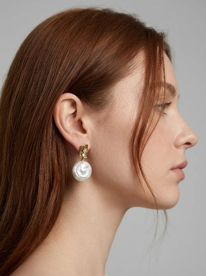 Profile of model with hair in a bun wearing the Roman Holiday coin baroque pearl drop earring