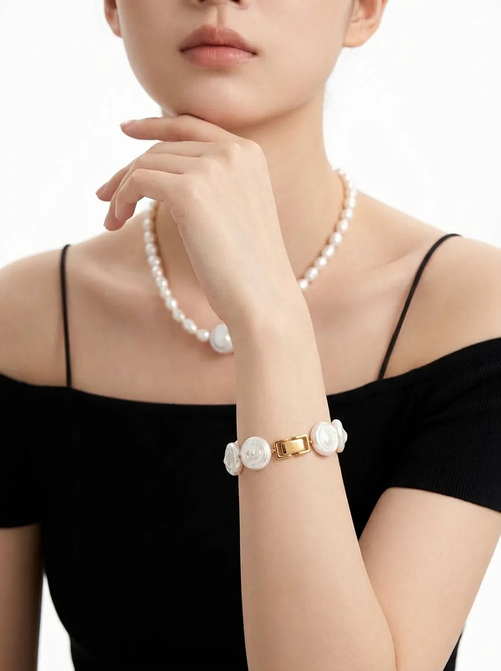 Model in off-shoulder black outfit wearing the Roman Holiday coin pearl bracelet showing gold clasp.