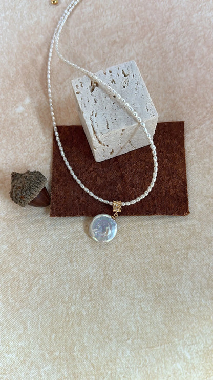 Roman coin pearl choker displayed over stone texture and pinecone props.