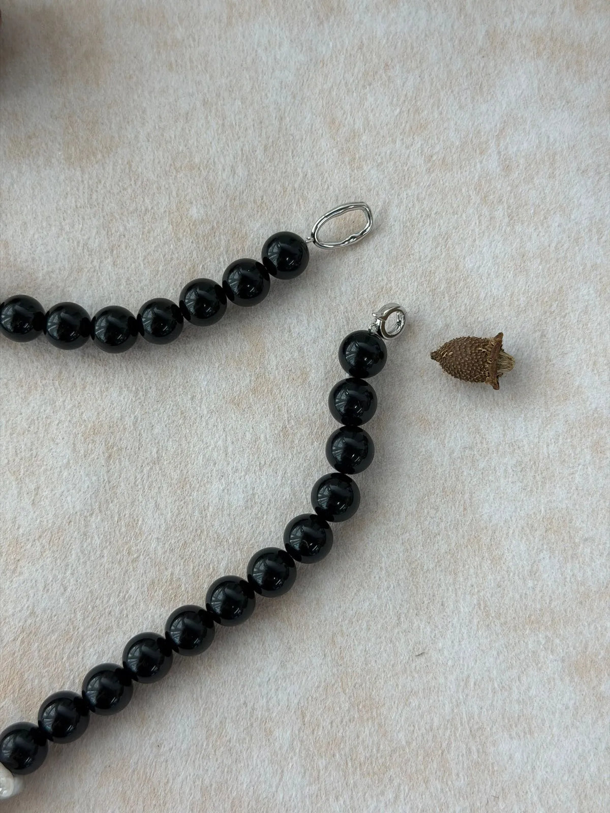 Close-up shot of the S925 sterling silver spring ring clasp and connector loop on the black onyx bead strand.
