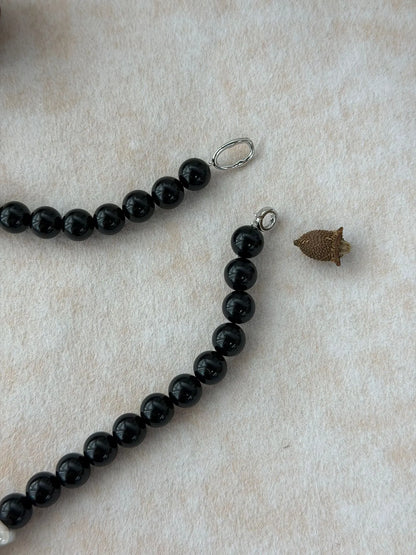 Close-up shot of the S925 sterling silver spring ring clasp and connector loop on the black onyx bead strand.