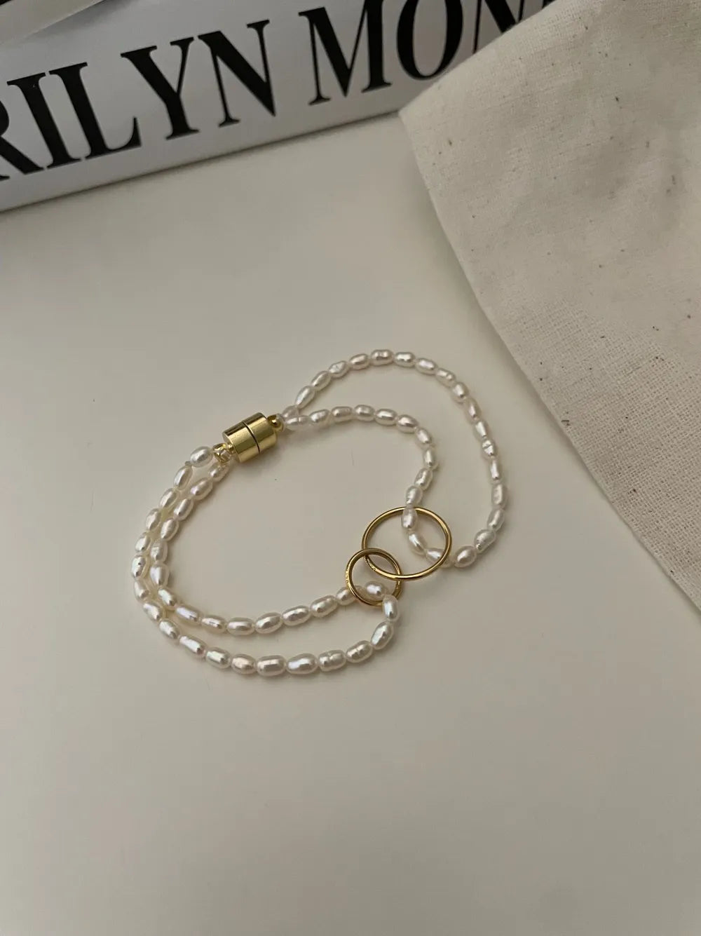 Double circle seed pearl layered bracelet resting next to a linen pouch.