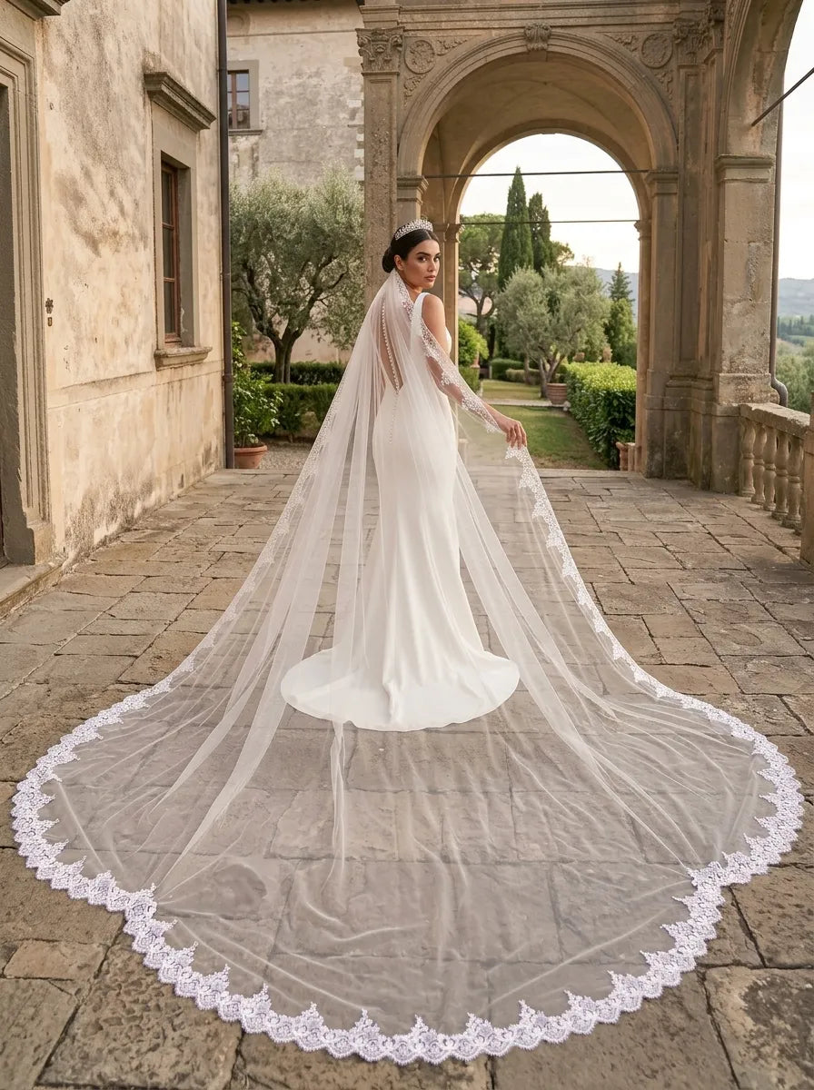 Bride in sleek white gown on historic villa terrace with wide sequin lace cathedral veil trailing