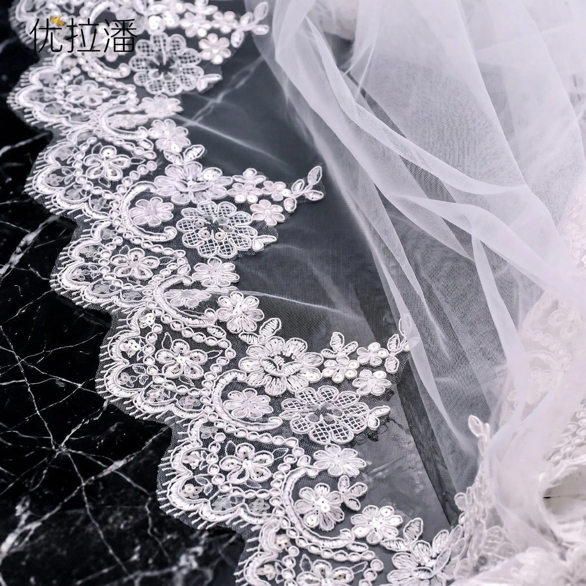 Close-up of floral sequin embroidery lace scallop edging on dark background