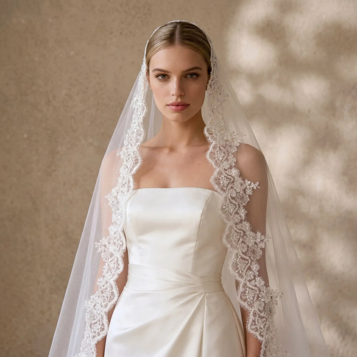 Portrait of bride wearing sheer lace veil draped over hair with embellished floral lace border